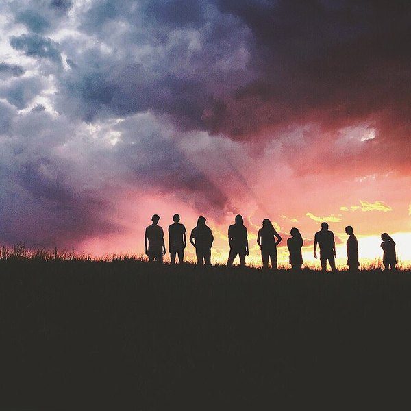 Un groupe de personnes en silhouette sous un ciel d’orage