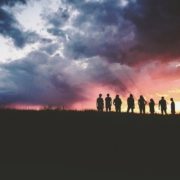 Un groupe de personnes en silhouette sous un ciel d’orage