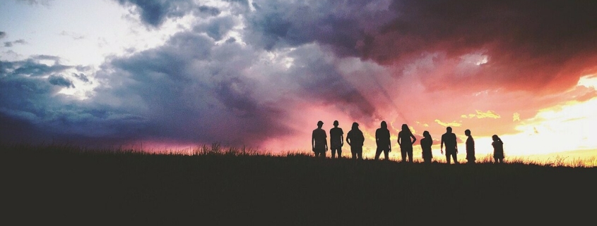 Un groupe de personnes en silhouette sous un ciel d’orage